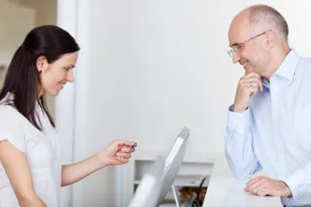 woman reading man's insurance card and entering it in the computer